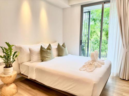 a white bedroom with a white couch and a window at Skypark Laguna Phuket by Escape Villas in Laguna Phuket