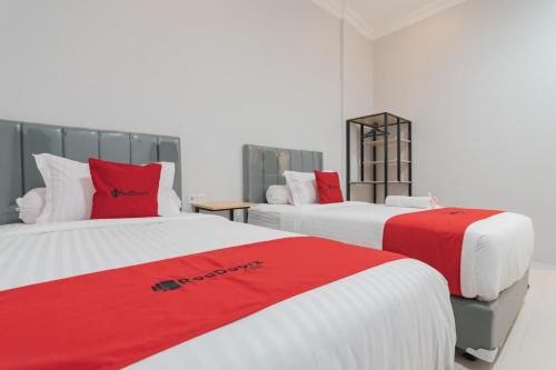 two beds in a room with red and white at RedDoorz Plus near Siloam Hospital Balikpapan in Balikpapan