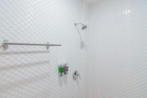 a shower in a bathroom with white tiles at RedDoorz Plus near Siloam Hospital Balikpapan in Balikpapan