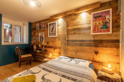 a bedroom with a wooden wall with a bed and a desk at Spa dans les Alpes in Desingy