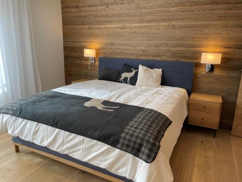 a bedroom with a bed with a wooden wall at Koller Sapuen by Arosa Holiday in Arosa