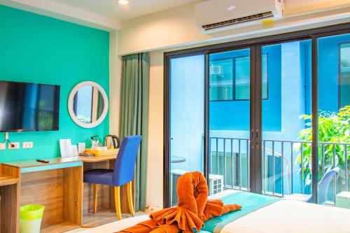 a bedroom with a bed and a desk and a balcony at Jomtien Beach Sleep Inn - Steps from Beach & Market in Jomtien Beach