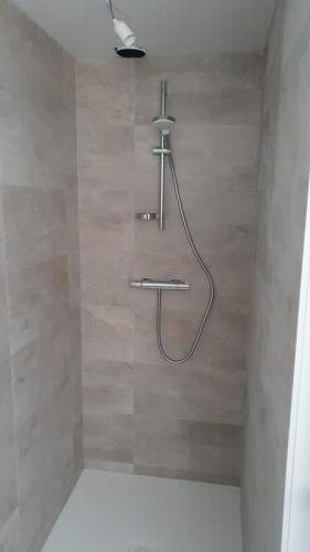 a shower with a hose attached to a wall at Joli appartement T3 in Allassac