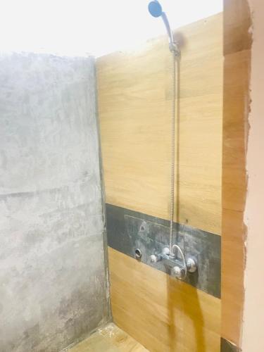 a shower in a bathroom with a wooden wall at Rahangala edge in Boralanda