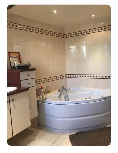 eine weiße Badewanne in einem Badezimmer mit Waschbecken in der Unterkunft Bugatti Chill in Moncé-en-Belin