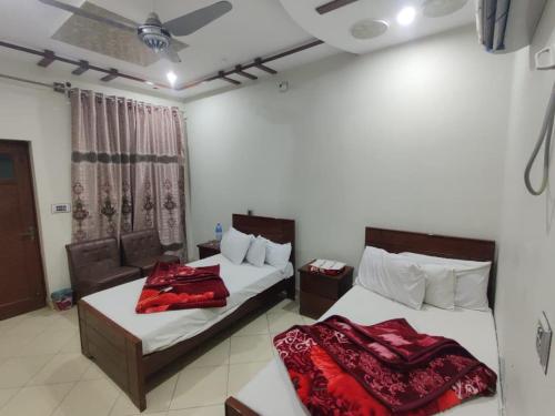 two beds in a hotel room with red blankets at Second Home Hotel in Multan