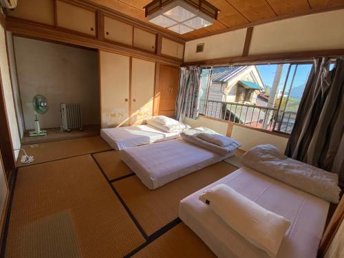 a room with two beds and a large window at Guesthouse Azumaya 2nd in Matsumoto