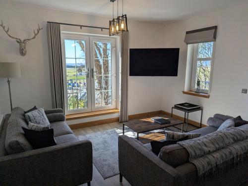 a living room with two couches and a tv at Royal Gardens Apartment 10 in Dornoch