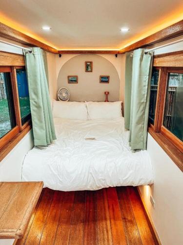 a bed in the middle of a room with windows at Jeepney Siargao in General Luna