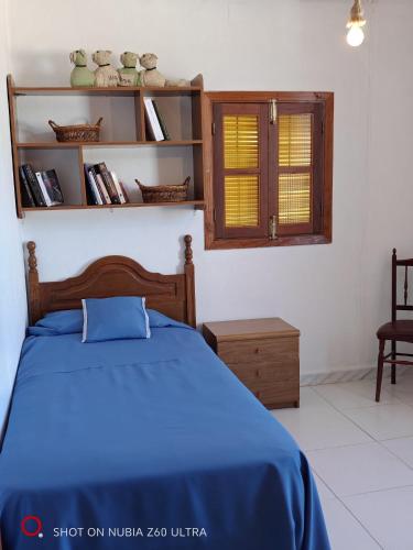 a bedroom with a blue bed and a window at casa el nacimiento in Igualeja