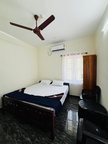 a bedroom with a bed and a ceiling fan at Babuloos Homestay in Varkala