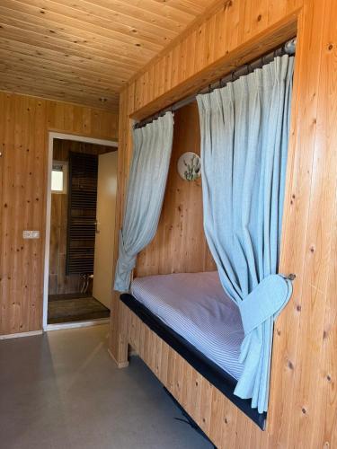 a bed in a wooden room with a window at vakantiehuisje Zusje met eigen sauna in Bruchterveld