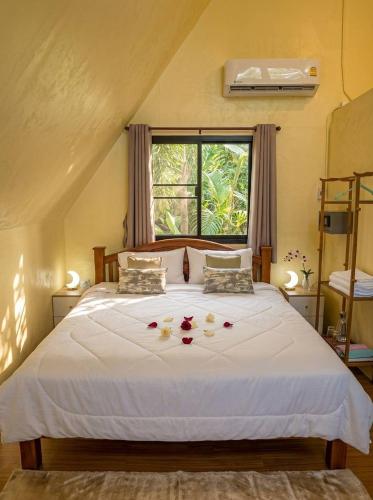 a bedroom with a white bed with flowers on it at Echo Falls Khanom in Ban Nua Tha