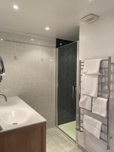 a bathroom with a sink and a shower with towels at Hotel Le Bellevue, Demeures & Chateaux in Villerville