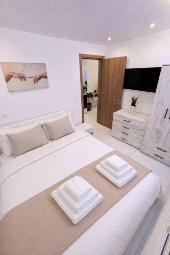 a large white bedroom with two pillows on a bed at BAS Garden Apartment Paralia in Paralia Katerinis