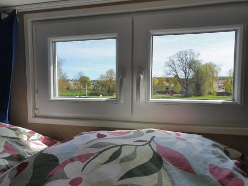 a bedroom with two windows and a bed with a comforter at Tinyhouse Rhön-Saale in Wülfershausen