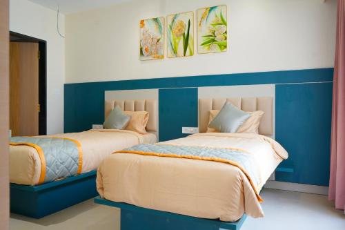 two beds in a room with blue and white at Vi Grand inn in Satyamangalam