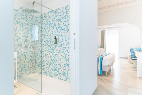 a bathroom with a glass shower with blue floral wallpaper at Luma Relais de Charme in Santa Teresa Gallura