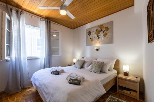 a bedroom with a white bed with a ceiling fan at Apartman Ana Lotre in Vela Luka