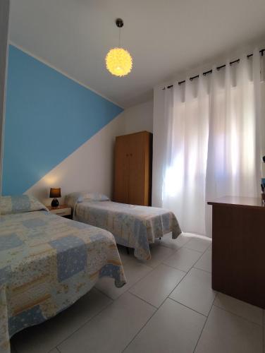 a bedroom with two beds and a blue wall at Civico 47 in Ogliastro Cilento