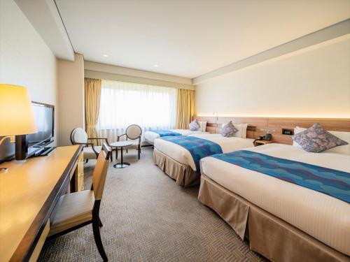 a hotel room with three beds and a television at KKR Hotel Hakata in Fukuoka