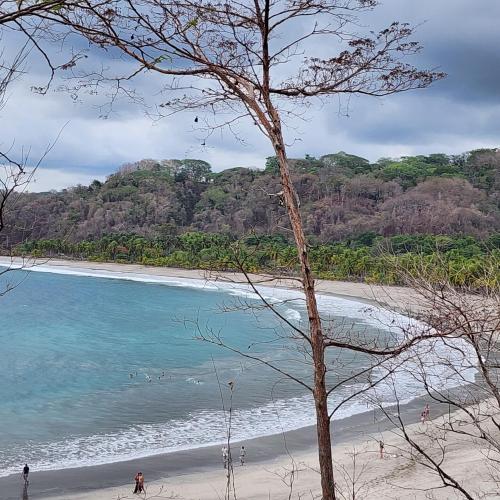 a beach with people walking on the sand and the water at Hostel Samara in Sámara