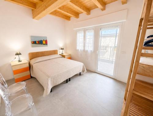 a white bedroom with a bed and a window at RESIDENCE PACE - Agenzia Cocal in Caorle
