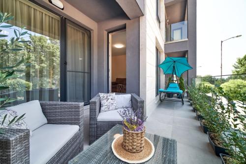 a patio with a couch and an umbrella on a balcony at 100m from the BEACH! ALDEA complex with pool in Kavarna