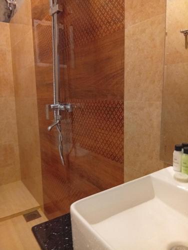 a shower with a glass door next to a sink at Holiday Apartment Ragama in Kurukulawa