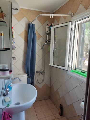 a bathroom with a sink and a shower with a window at Anastasia's Cottage in Oikhalía