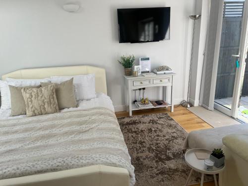 a bedroom with a bed and a tv on a wall at Garden Lodge, boutique - Walton on Thames in Walton-on-Thames
