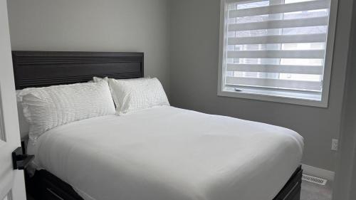 a white bed in a bedroom with a window at Home Sweet Home in Ottawa