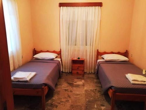 ein Schlafzimmer mit zwei Betten und einem Fenster mit Vorhang in der Unterkunft Eleni's house in Masouri