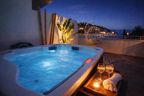a hot tub on a balcony with wine glasses at Casa del Sol Jacuzzi privado y vistas al Mediterráneo en Altea Hills in Altea