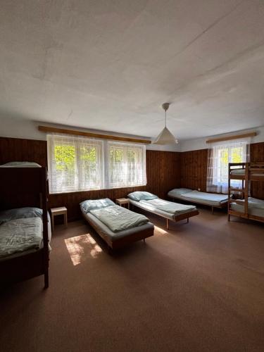 a room with three beds in it with windows at Kemp Oparno, bezvakempy in Malé Žernoseky