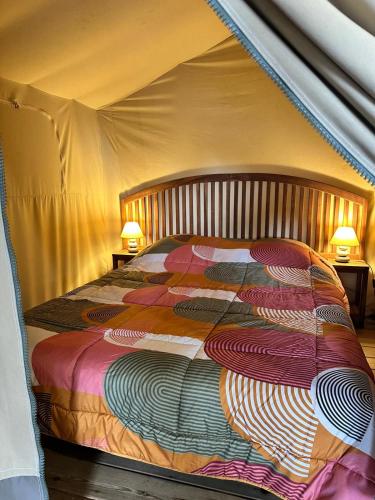 a large bed in a tent with two lamps at Camping Le Sans Souci in Fresnay-sur-Sarthe