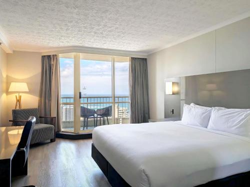 a hotel room with a large bed and a balcony at Novotel Surfers Paradise in Gold Coast