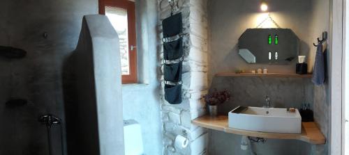 a bathroom with a white sink and a window at Tinos Ecolodge in Tinos