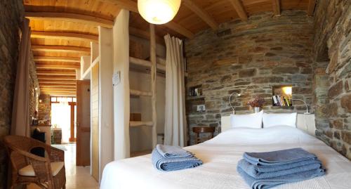 a bedroom with a large bed in a stone wall at Tinos Ecolodge in Tinos