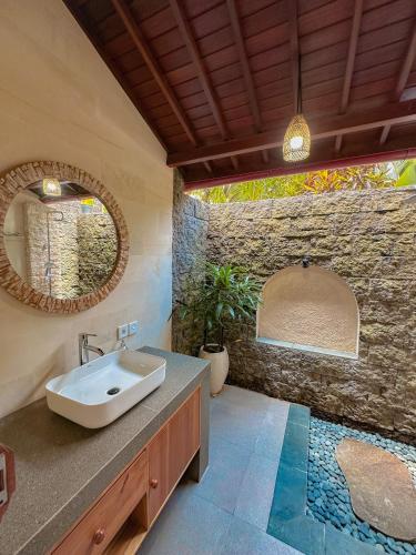 a bathroom with a sink and a stone wall at Kukuh House Ubud in Ubud