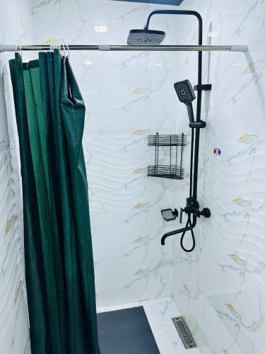 a shower with a green shower curtain in a bathroom at Guest House Bekturdi in Khiva