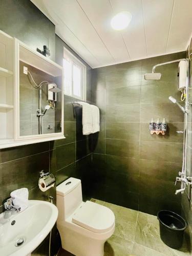 a bathroom with a white toilet and a sink at KRUEGERs Cottage in Sipalay