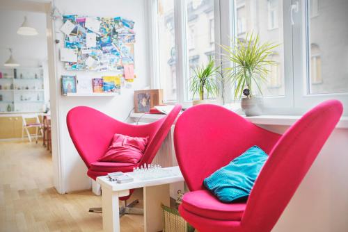 2 chaises rouges et une table dans une pièce dans l'établissement The Dots Hostel, à Zagreb