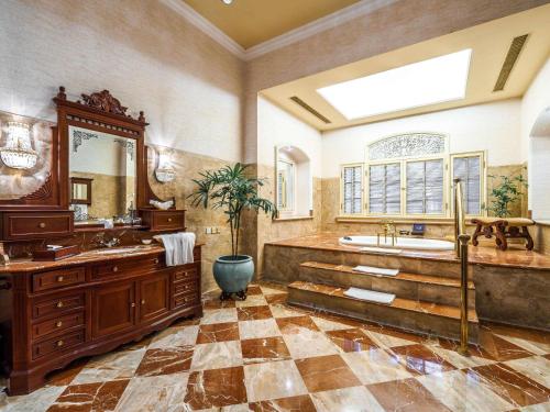 a large bathroom with a large tub and a sink at Hotel Majapahit Surabaya MGallery in Surabaya