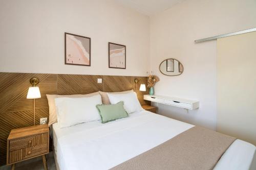 a bedroom with a white bed with a wooden headboard at Mesogitonia House in Zekros