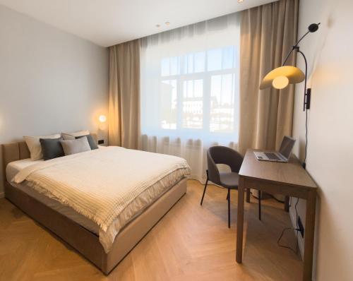 a bedroom with a bed and a desk with a laptop at NIDO Park view in Daugavpils