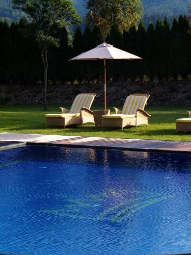 two chairs and an umbrella next to a swimming pool at Sporthotel Ellmau in Tirol in Ellmau