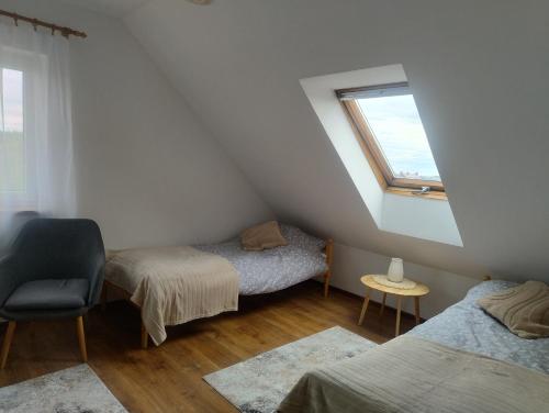 a attic room with two beds and a window at Ostoja Jaczno in Smolniki