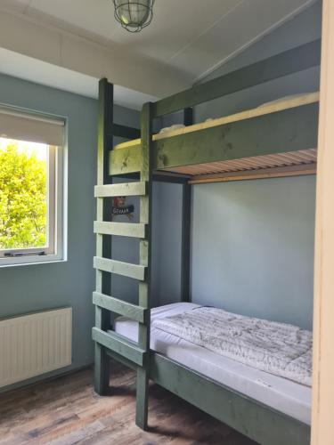 a bedroom with two bunk beds and a window at Bungalow Nathalie in Julianadorp
