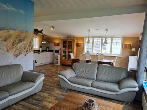 a living room with two couches and a kitchen at Bungalow Nathalie in Julianadorp